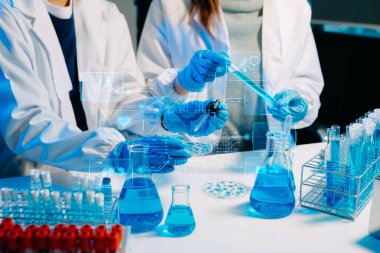 Laboratuvar önlüklü bilim adamları, sanal ekranlı modern bir yüksek teknoloji laboratuvarında kimyasallarla çalışıyorlar.