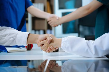 Doktor el sıkışması ve sağlık hizmetlerinde ortaklık, ilaç veya işbirliği, birlik veya destek için güven. Tıp uzmanlarından oluşan bir ekip klinik veya konukseverlikte veya klinikte başarı için takım çalışması veya el sıkışıyor