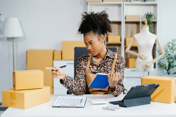 Молодая владелица бизнеса женщина подготовить посылки коробки и проверить онлайн заказы для доставки заказчику. Концепция покупок онлайн.