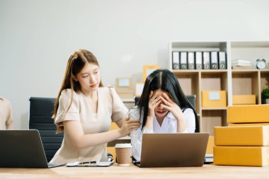 Young Asian businesswomen prepare parcel boxes. They are stressed, bored and overthinking from working but standing check online orders for deliver to customer clipart