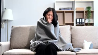 Kanepede oturan genç Asyalı kadın ve öksürük, hastalık konsepti