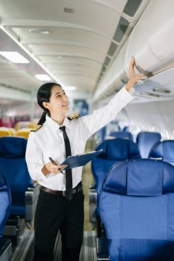 Asyalı kendinden emin, üniformalı kadın pilot uçağın içinde duruyor.