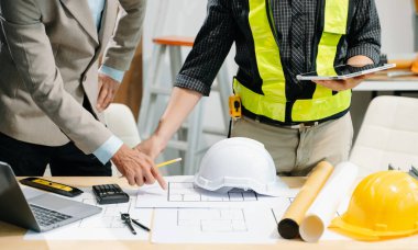 Mimaride profesyonel işbirliği. İki mühendis inşaat planları ve ev modeli projesi üzerinde çalışıyor.