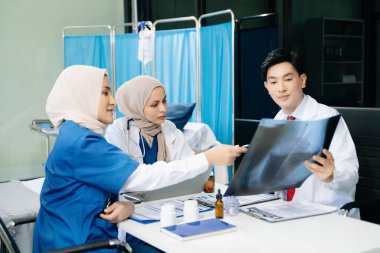 Doktorlar ve hemşireler bir hastane koğuşunda röntgen taramasını tartışırken profesyonellik ve takım çalışması sergiliyorlar.