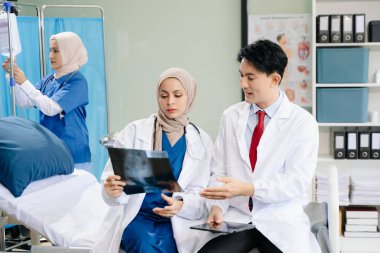 Doktorlar ve hemşireler bir hastane koğuşunda röntgen taramasını tartışırken profesyonellik ve takım çalışması sergiliyorlar.