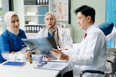 Doktorlar ve hemşireler bir hastane koğuşunda röntgen taramasını tartışırken profesyonellik ve takım çalışması sergiliyorlar.