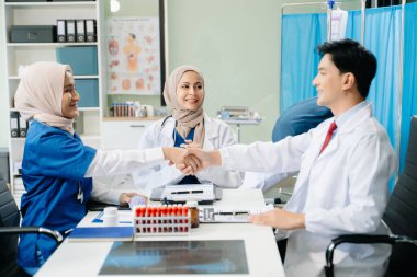 Doktorlar ve hemşireler hastane koğuşunda birlikte çalışırken el sıkışırken profesyonellik ve takım çalışması sergiliyorlar.