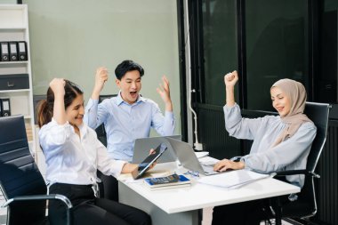 Mutlu Asyalı iş adamları modern ofiste yeni bir projede birlikte çalışıyorlar. 