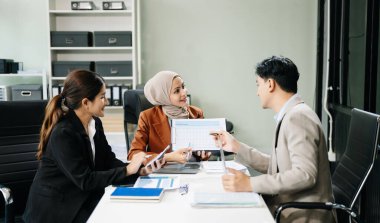 Mutlu Asyalı iş adamları modern ofiste yeni bir projede birlikte çalışıyorlar. 