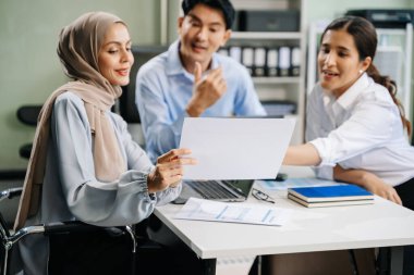 Mutlu Asyalı iş adamları modern ofiste yeni bir projede birlikte çalışıyorlar. 