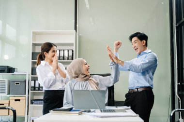 Mutlu Asyalı iş adamları modern ofiste yeni bir projede birlikte çalışıyorlar. 