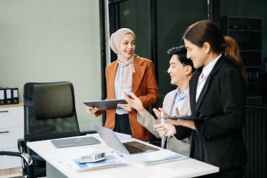 Mutlu Asyalı iş adamları modern ofiste yeni bir projede birlikte çalışıyorlar. 