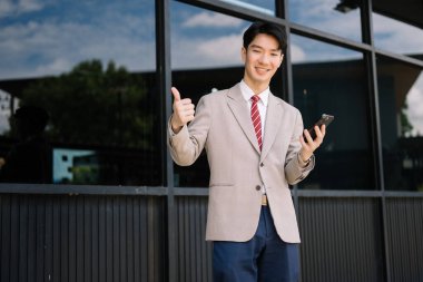Genç Asyalı işadamı, büyük şehirde akıllı telefon kullanıyor. 