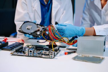 Laboratuvar önlüklü işçiler uzman bilgisayar donanımı montajı ve sabit disk kurulumunu hassas ve ileri teknoloji bilişim ve elektronik meraklıları için sergiliyorlar.. 