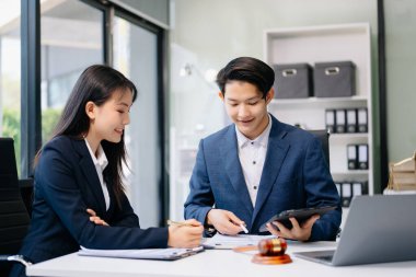 Asyalı erkek avukat modern ofiste iş kadınıyla sözleşme belgelerini tartışıyor. Masasında adalet terazisi olan Gavel.. 