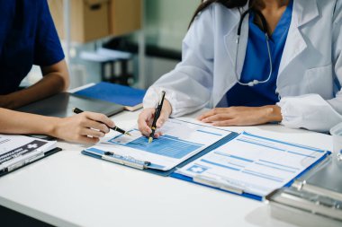 Tıbbi raporlar üzerinde çalışan ve dizüstü bilgisayar kullanan iki doktorun orta bölümü..