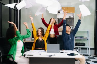 Çeşitli takımlar başarıyı kutluyor, kağıtları canlı ofis ortamında fırlatıyor, neşe, takım çalışması ve profesyonel işbirliği anları yakalıyor.