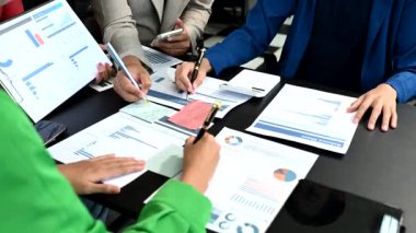 Belgeler üzerinde bilgi grafikleriyle notlar alırken, görevdeki işadamları