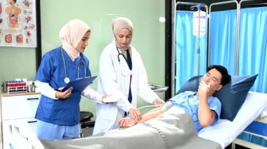 Kadın doktorlar hastane koğuşundaki hastaya kan basıncını ölçüyorlar. Profesyonellik ve takım çalışması sergiliyorlar.