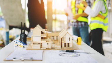 Ofisteki ev modeli ve arka plan üzerinde çalışan mimarlar 