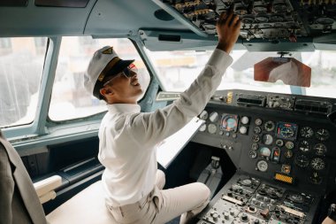 Üniformalı Asyalı özgüvenli erkek pilot uçak kokpitinin içinde oturuyor.
