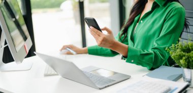 İş kadınının iş yerinde akıllı telefon, laptop ve bilgisayar kullandığı orta bölüm..