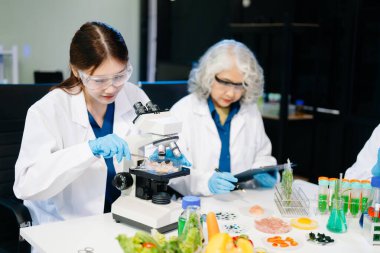 Laboratuvar önlüklü gıda bilimcileri, numuneleri test ediyor ve modern bir laboratuvar ortamında gıda güvenliği ve kalitesini analiz ediyorlar..