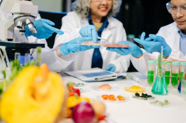 Bir laboratuarda mikroskop ve laboratuvar ekipmanları kullanarak yiyecek araştırması yapan Asyalı bilim adamları ekibi, gıda bilimi ve biyoteknoloji alanında yenilik sergiliyor.