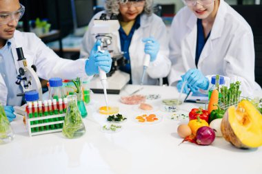 Bir laboratuarda mikroskop ve laboratuvar ekipmanları kullanarak yiyecek araştırması yapan Asyalı bilim adamları ekibi, gıda bilimi ve biyoteknoloji alanında yenilik sergiliyor.