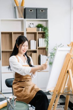 Sanat atölyesinde resim yapan Asyalı kadın ressam, boya malzemeleri, yağ boyaları, sanat stüdyosunda yaratıcı alan kullanıyor. 