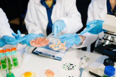 Laboratuvardaki Asyalı bilim adamları mikroskop ve laboratuvar ekipmanları kullanarak gıda araştırmaları yapıyor, gıda bilimi ve biyoteknoloji alanında yenilikler sergiliyorlar.