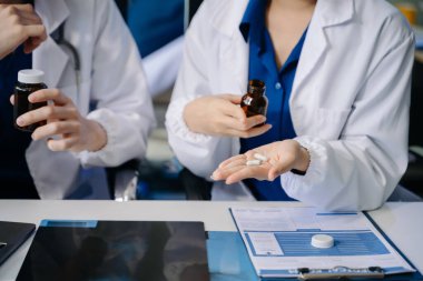 İki doktorun orta bölümü, hastanedeki masada ilaç kullanımını açıklıyor. 