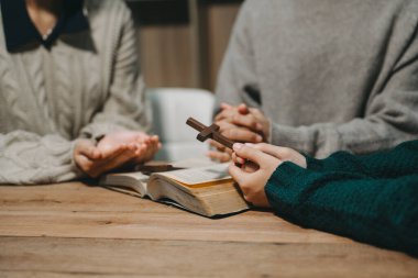 Hıristiyanlar, Allah 'ın lütfunu kazanmak için el ele tutuşurlar. Tahta masada.