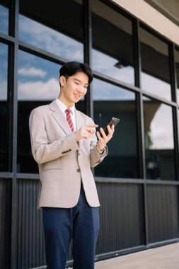 Genç Asyalı işadamı büyük şehirde akıllı telefon kullanıyor.