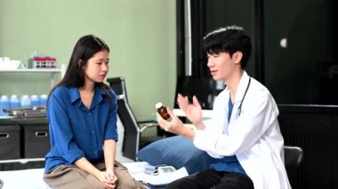 Asyalı erkek doktor hastanedeki kadın hastaya nasıl hap içileceğini anlatıyor. 