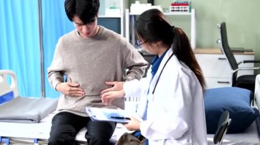 Asyalı kadın doktor erkek hastayı hastane yatağında kontrol ediyor.  