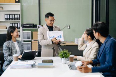  Genç iş adamları beyin fırtınası yapıyor, bilgisayar ve tablet kullanarak iş planlıyorlar ve tartışıyorlar.