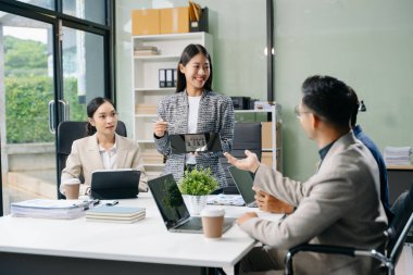  Genç iş adamları beyin fırtınası yapıyor, bilgisayar ve tablet kullanarak iş planlıyorlar ve tartışıyorlar.