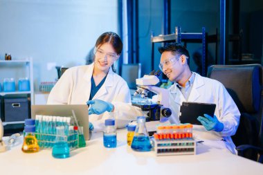 Bir tıp laboratuvarında araştırma yapan bilim adamları bunlardan biri mikroskop kullanıyor.. 