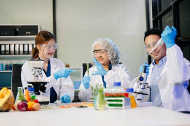 Laboratuvar önlüklü gıda bilimcileri, numuneleri test ediyorlar ve modern bir laboratuvarda gıda güvenliğini ve kalitesini analiz ediyorlar. 