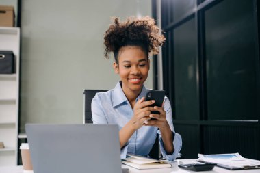 Ofiste çalışırken dizüstü bilgisayar ve akıllı telefon kullanan kadın girişimci 