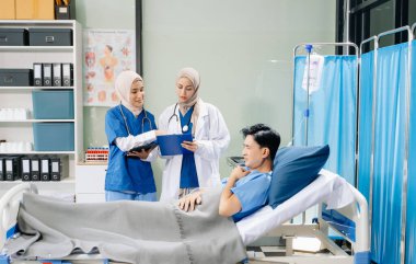 Hastane koğuşundaki bir hastaya bakım sunan tesettürlü doktorlar takım çalışması, profesyonellik ve şefkatli bir sağlık ortamı sunuyorlar..