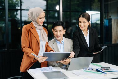 Ofisteki dizüstü bilgisayarları kullanarak yeni bir projede işbirliği yapan işadamları