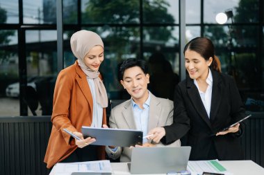 Ofisteki dizüstü bilgisayarları kullanarak yeni bir projede işbirliği yapan işadamları