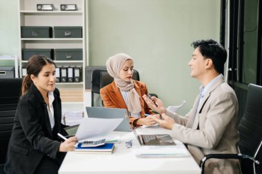 Ofisteki dizüstü bilgisayarları kullanarak yeni bir projede işbirliği yapan işadamları