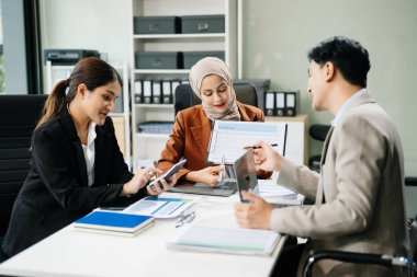 Ofisteki dizüstü bilgisayarları kullanarak yeni bir projede işbirliği yapan işadamları