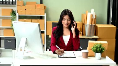 Küçük işletme KOBİ 'si kurun. İş kadını akıllı telefondan konuşuyor ve online alışveriş siparişini almak ve kontrol etmek için bilgisayarı kullanıyor.