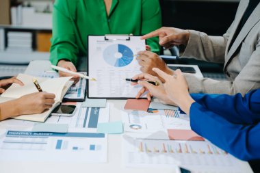 İş ekibi ofisteki mali verilerle tartışıyor, çalışıyor ve analiz ediyor.