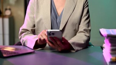 Gece geç saatlerde iş kadınının akıllı telefonuyla çalıştığı bölümün ortasında. fazla mesai konsepti 