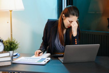 Asyalı kadın migren ağrısı çekiyor. Ofiste dizüstü bilgisayar kullanan çok çalışan bir iş kadını. 